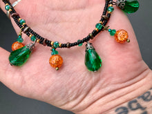 Load image into Gallery viewer, This necklace is the perfect addition to any collection, boasting a dark, elegant aesthetic inspired by nature. Comprised of two strands of glass beads with a variety of shapes and colors, it offers subtle autumnal vibrancy with its orange and green pumpkin-shaped glass beads. This piece is full of shimmer and complexity, providing unique depth and flair. Necklace is 16 1/2” in length, can be adjusted up to 18 1/2"