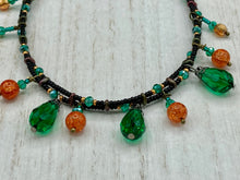 Load image into Gallery viewer, This necklace is the perfect addition to any collection, boasting a dark, elegant aesthetic inspired by nature. Comprised of two strands of glass beads with a variety of shapes and colors, it offers subtle autumnal vibrancy with its orange and green pumpkin-shaped glass beads. This piece is full of shimmer and complexity, providing unique depth and flair. Necklace is 16 1/2” in length, can be adjusted up to 18 1/2"