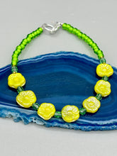 Load image into Gallery viewer, This delicate jewelry displays an array of gentle hues, vibrant yet soft.This light yellow pressed glass floral beaded bracelet and earrings set features an iridescent shimmer finish and is crafted with metal wire and a lobster claw clasp for easy closure. Measurements: Bracelet: 8 1/2" in length Earrings: 1 1/4" length