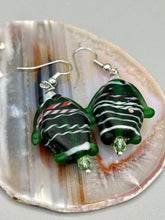 Load image into Gallery viewer, These nature-inspired glass fish earrings are the perfect addition to your boho look. Featuring a delightful dark green hue, the large puffy fish will bring a hippie vibe to your style. Measurements: 1 1/2” in length
