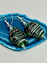 Load image into Gallery viewer, These nature-inspired glass fish earrings are the perfect addition to your boho look. Featuring a delightful dark green hue, the large puffy fish will bring a hippie vibe to your style. Measurements: 1 1/2” in length