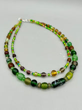 Load image into Gallery viewer, Two strands of beads compose this necklace, featuring a striking combination of light and dark greens, amber, golds, and dark browns. A mixture of glass and metal beads with patina color adds texture and beauty to this unique, bold statement piece. Measurements: Necklace is 17 1/2” in length, can be adjusted up to 19"