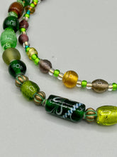 Load image into Gallery viewer, Two strands of beads compose this necklace, featuring a striking combination of light and dark greens, amber, golds, and dark browns. A mixture of glass and metal beads with patina color adds texture and beauty to this unique, bold statement piece. Measurements: Necklace is 17 1/2” in length, can be adjusted up to 19"