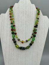 Load image into Gallery viewer, Two strands of beads compose this necklace, featuring a striking combination of light and dark greens, amber, golds, and dark browns. A mixture of glass and metal beads with patina color adds texture and beauty to this unique, bold statement piece. Measurements: Necklace is 17 1/2” in length, can be adjusted up to 19"