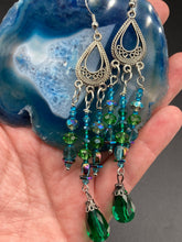 Load image into Gallery viewer, This Whimsical Blue Green Peacock Inspired Beaded Earrings set features bold chandelier style earrings with three long strands of glass bead. These show-stopping pieces boast a range of shimmering shades of blue, green, purple, and gold. A perfect addition to any fashionista's collection. Measurements: 3 1/2” in length