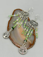 Load image into Gallery viewer, Be mesmerized by these large cascade style earrings, featuring five delicate strands of light green, iridescent and gold-tone beads with a tree of life charm for an eye-catching effect. Perfect for whimsical, nature-inspired looks, these earrings will liven up any outfit. Measurements: 3 3/4” in length