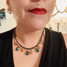 Load image into Gallery viewer, This necklace is the perfect addition to any collection, boasting a dark, elegant aesthetic inspired by nature. Comprised of two strands of glass beads with a variety of shapes and colors, it offers subtle autumnal vibrancy with its orange and green pumpkin-shaped glass beads. This piece is full of shimmer and complexity, providing unique depth and flair. Necklace is 16 1/2” in length, can be adjusted up to 18 1/2"