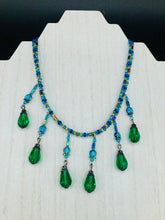 Load image into Gallery viewer, This Victorian-style necklace features a combination of green and blue glass beads, and rectangular, rainbow hematite beads for a layered and textured effect. The dramatic dark-green glass tear drops dangling from the strands provide additional depth and sophistication. Double-hole flat matte blue beads are used to hold the two strands together, creating a collar-like shape that softly cascades over your neckline. It is a striking, bold and elegant accessory.