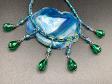 Load image into Gallery viewer, This Victorian-style necklace features a combination of green and blue glass beads, and rectangular, rainbow hematite beads for a layered and textured effect. The dramatic dark-green glass tear drops dangling from the strands provide additional depth and sophistication. Double-hole flat matte blue beads are used to hold the two strands together, creating a collar-like shape that softly cascades over your neckline. It is a striking, bold and elegant accessory.