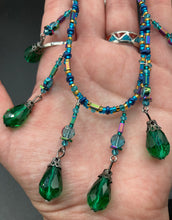Load image into Gallery viewer, This Victorian-style necklace features a combination of green and blue glass beads, and rectangular, rainbow hematite beads for a layered and textured effect. The dramatic dark-green glass tear drops dangling from the strands provide additional depth and sophistication. Double-hole flat matte blue beads are used to hold the two strands together, creating a collar-like shape that softly cascades over your neckline. It is a striking, bold and elegant accessory.