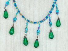Load image into Gallery viewer, This Victorian-style necklace features a combination of green and blue glass beads, and rectangular, rainbow hematite beads for a layered and textured effect. The dramatic dark-green glass tear drops dangling from the strands provide additional depth and sophistication. Double-hole flat matte blue beads are used to hold the two strands together, creating a collar-like shape that softly cascades over your neckline. It is a striking, bold and elegant accessory.