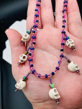 Load image into Gallery viewer, Dark gothic, elegant, and romantic necklace contains two beaded strands of pink beads that contain a dash of purple, blue, and gold hues. Tiny skull howlite skulls with rainbow hematite heart shaped beads to give this necklace a cute and romantic style. Comes with matching earrings. Necklace is 14”adjustable up to 18" in length - hanging skulls and hearts pendant are 1”