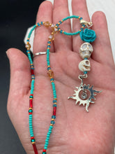 Load image into Gallery viewer, Enchanting Southwest Style Jewelry. Necklace captures Frida Kahlo's signature floral crown on her head. Howlite skull beads topped with turquoise quartize floral beads, style to represent mother and child. Dangling shimmery sun charm pendant to incorporated some movement. Chingona, Cabrona, Latina Chicana, Goth, Vampire Goth, Dark Witchy Style. This piece of jewelry can be worn for inspiration or a great Dia De Los Muertos jewelry piece. Necklace is 20” in length - flower, skull, and sun pendant is 3”
