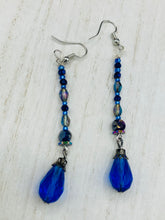 Load image into Gallery viewer, This stunning, one of a kind pair of celestial beaded earrings is a bold addition to any jewelry collection. Crafted with vibrant blue glass beads, the color contains varied shades of blue, purple, and hints of gold to create unique texture. The design is inspired by the awe-inspiring beauty of the majestic galaxy. Measurements: 2 3/4” in length