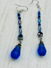 Load image into Gallery viewer, This stunning, one of a kind pair of celestial beaded earrings is a bold addition to any jewelry collection. Crafted with vibrant blue glass beads, the color contains varied shades of blue, purple, and hints of gold to create unique texture. The design is inspired by the awe-inspiring beauty of the majestic galaxy.  Measurements: 2 3/4 ” in length