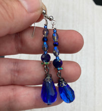 Load image into Gallery viewer, This stunning, one of a kind pair of celestial beaded earrings is a bold addition to any jewelry collection. Crafted with vibrant blue glass beads, the color contains varied shades of blue, purple, and hints of gold to create unique texture. The design is inspired by the awe-inspiring beauty of the majestic galaxy. Measurements: 2” in length