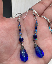 Load image into Gallery viewer, This stunning, one of a kind pair of celestial beaded earrings is a bold addition to any jewelry collection. Crafted with vibrant blue glass beads, the color contains varied shades of blue, purple, and hints of gold to create unique texture. The design is inspired by the awe-inspiring beauty of the majestic galaxy. Measurements: 2” in length