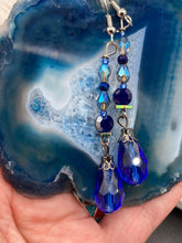 Load image into Gallery viewer, This stunning, one of a kind pair of celestial beaded earrings is a bold addition to any jewelry collection. Crafted with vibrant blue glass beads, the color contains varied shades of blue, purple, and hints of gold to create unique texture. The design is inspired by the awe-inspiring beauty of the majestic galaxy. Measurements: 2” in length