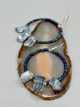 Load image into Gallery viewer, These ultra-trendy crystal nugget and glass beaded hoop earrings are perfect for any hippie or bohemian look. The dark blue glass beads give off an iridescent shimmer and blend brilliantly with the luster blue crystals, creating an eye catching contrast and a unique touch of nature-inspired beauty. Measurements: 2 1/4" length