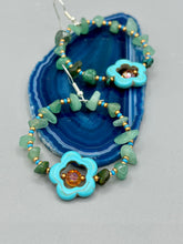 Load image into Gallery viewer, This pair of earrings features a turquoise magnesite floral bead with a vibrant orange glass bead and natural green aventurine stone chips juxtaposed against gold and blue glass beads. Measurements: 2" length