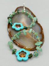 Load image into Gallery viewer, This pair of earrings features a turquoise magnesite floral bead with a vibrant orange glass bead and natural green aventurine stone chips juxtaposed against gold and blue glass beads. Measurements: 2" length