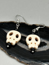 Load image into Gallery viewer, These stylish skull earrings are perfect for adding a unique flair to any outfit. Whether you're looking for a Dia De Los Muertos accessory or simply looking to draw inspiration, these goth pieces perfectly capture the vampire goth, witchy, dark, Chingona Cabrona, Latina Chicana styles.  Measurements: 1 1/4 ” in length