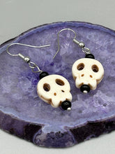 Load image into Gallery viewer, These stylish skull earrings are perfect for adding a unique flair to any outfit. Whether you're looking for a Dia De Los Muertos accessory or simply looking to draw inspiration, these goth pieces perfectly capture the vampire goth, witchy, dark, Chingona Cabrona, Latina Chicana styles.  Measurements: 1 1/4 ” in length