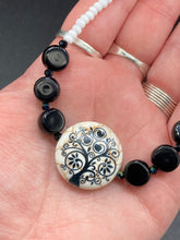 Load image into Gallery viewer, This impressive 24mm reconstituted quartzite lentil bead creates an eye-catching statement piece. The black and white glass beads add a sophisticated touch to its understated tree print. Perfectly suited to casual and formal occasions alike, this stunning necklace will complete any look. It was inspired by the stunning landscapes found in the U.S. National Arboretum in D.C. Measurements: Necklace is 17 " in length