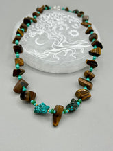 Load image into Gallery viewer, This bold earthy tone necklace presents an eye-catching combination of natural tigers eye stone chips and blue-green turquoise glass beads, making it an ideal statement piece. Measurements: Necklace is 18 3/4 " in length adjustable to 20"