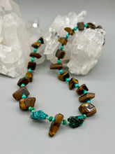 Load image into Gallery viewer, Bold earthy tone necklace contains large natural tigers eye stone chips with blue and green turquoise glass beads. Colorful and bold strand will make a perfect statement piece. Measurements: Necklace is 18 3/4 " in length adjustable to 20"This bold earthy tone necklace presents an eye-catching combination of natural tigers eye stone chips and blue-green turquoise glass beads, making it an ideal statement piece. Measurements: Necklace is 18 3/4 " in length adjustable to 20"