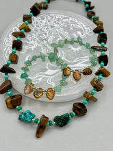 Load image into Gallery viewer, Bold earthy tone necklace contains large natural tigers eye stone chips with blue and green turquoise glass beads. Measurements: Necklace is 18 3/4 " in length adjustable to 20"These Aventurine Stone Chip Beaded Hoop Earrings feature natural aventurine stone chips, turquoise, and gold glass beads. The amber-tone pressed glass leaf charm has an iridescent shimmer finish, with subtle accents of gold, purple, blue, and pink. Measurements: 2" length