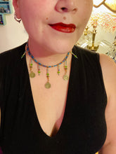 Load image into Gallery viewer, This collar-style necklace is a showstopper, beaded with stylish glass beads in green and blue tones, featuring contrasting yin-yang charms with differing sides. Rectangular rainbow hematite beads add complexity and depth, and double-hole matte gold beads keep the collar shape complete. It gracefully drapes around the neck, making a timeless statement of elegance.  Measurements:  Necklace is 14”, can be adjusted up to 18"