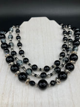 Load image into Gallery viewer, This stunning Shimmery black glass and floral metal beaded necklace features three long strands which gracefully drape around the neck. Its bold elegance is the perfect accessory for a cocktail chic outfit, a wedding, or a more minimalist look.  Measurements:    Necklace is 16 1/4” in length - adjustable to 18"