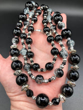 Load image into Gallery viewer, This stunning Shimmery black glass and floral metal beaded necklace features three long strands which gracefully drape around the neck. Its bold elegance is the perfect accessory for a cocktail chic outfit, a wedding, or a more minimalist look.  Measurements:    Necklace is 16 1/4” in length - adjustable to 18"