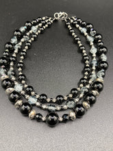 Load image into Gallery viewer, This stunning Shimmery black glass and floral metal beaded necklace features three long strands which gracefully drape around the neck. Its bold elegance is the perfect accessory for a cocktail chic outfit, a wedding, or a more minimalist look.  Measurements:    Necklace is 16 1/4” in length - adjustable to 18"