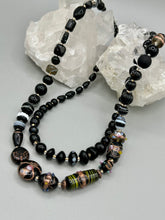 Load image into Gallery viewer, Add flair to your look with this unique large and chunky hand beaded necklace. Featuring a wide variety of mixed black glass beads in different sizes and shapes, this intricately-crafted statement piece offers a bold, hippie-chic, shabby-chic, and bohemian style. Measurements: Necklace is 18” in length, can be adjusted up to 20"