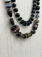 Load image into Gallery viewer, Add flair to your look with this unique large and chunky hand beaded necklace. Featuring a wide variety of mixed black glass beads in different sizes and shapes, this intricately-crafted statement piece offers a bold, hippie-chic, shabby-chic, and bohemian style. Measurements: Necklace is 18” in length, can be adjusted up to 20"
