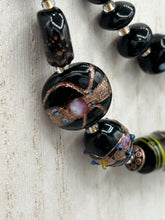 Load image into Gallery viewer, Add flair to your look with this unique large and chunky hand beaded necklace. Featuring a wide variety of mixed black glass beads in different sizes and shapes, this intricately-crafted statement piece offers a bold, hippie-chic, shabby-chic, and bohemian style. Measurements: Necklace is 18” in length, can be adjusted up to 20"