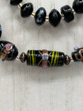 Load image into Gallery viewer, Add flair to your look with this unique large and chunky hand beaded necklace. Featuring a wide variety of mixed black glass beads in different sizes and shapes, this intricately-crafted statement piece offers a bold, hippie-chic, shabby-chic, and bohemian style. Measurements: Necklace is 18” in length, can be adjusted up to 20"