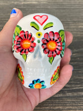 Load image into Gallery viewer, Inspired by nature, ceramic skull is full of vibrant colors and intricate details. The primary color is white with a black cat silhouette and multi-color floral motifs, along with hearts and leaves and lively colorful accents around the entire skull. Mini skull represented the eternal love for a special kitty cat in your life. Black cat silhouette is sitting on a tree branch admiring the starry night sky. Art created for all the cat lovers who adore their sweet kitty. Measurements: H 2 3/4” x W 2” x D 2”