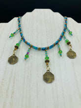 Load image into Gallery viewer, This collar-style necklace is a showstopper, beaded with stylish glass beads in green and blue tones, featuring contrasting yin-yang charms with differing sides. Rectangular rainbow hematite beads add complexity and depth, and double-hole matte gold beads keep the collar shape complete. It gracefully drapes around the neck, making a timeless statement of elegance.  Measurements:  Necklace is 14”, can be adjusted up to 18"