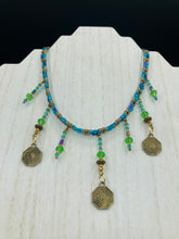Load image into Gallery viewer, This collar-style necklace is a showstopper, beaded with stylish glass beads in green and blue tones, featuring contrasting yin-yang charms with differing sides. Rectangular rainbow hematite beads add complexity and depth, and double-hole matte gold beads keep the collar shape complete. It gracefully drapes around the neck, making a timeless statement of elegance.  Measurements:  Necklace is 14”, can be adjusted up to 18"