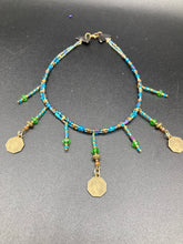 Load image into Gallery viewer, This collar-style necklace is a showstopper, beaded with stylish glass beads in green and blue tones, featuring contrasting yin-yang charms with differing sides. Rectangular rainbow hematite beads add complexity and depth, and double-hole matte gold beads keep the collar shape complete. It gracefully drapes around the neck, making a timeless statement of elegance.  Measurements:  Necklace is 14”, can be adjusted up to 18"