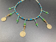 Load image into Gallery viewer, This collar-style necklace is a showstopper, beaded with stylish glass beads in green and blue tones, featuring contrasting yin-yang charms with differing sides. Rectangular rainbow hematite beads add complexity and depth, and double-hole matte gold beads keep the collar shape complete. It gracefully drapes around the neck, making a timeless statement of elegance.  Measurements:  Necklace is 14”, can be adjusted up to 18"