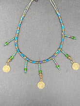 Load image into Gallery viewer, This collar-style necklace is a showstopper, beaded with stylish glass beads in green and blue tones, featuring contrasting yin-yang charms with differing sides. Rectangular rainbow hematite beads add complexity and depth, and double-hole matte gold beads keep the collar shape complete. It gracefully drapes around the neck, making a timeless statement of elegance.  Measurements:  Necklace is 14”, can be adjusted up to 18"