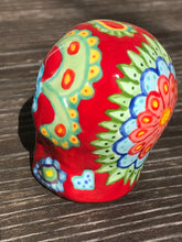 Load image into Gallery viewer, This hand-painted Mini Dia de Los Muertos ceramic skull art provides a vibrant representation of summertime blooms. Its fire red and nature-inspired design is unique, capturing the energy and beauty of a hot day at Meadowlark Gardens in Virginia. A perfect addition to any art collection. Measurements: H 2 3/4” x W 2” x D 2”