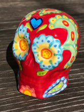 Load image into Gallery viewer, This hand-painted Mini Dia de Los Muertos ceramic skull art provides a vibrant representation of summertime blooms. Its fire red and nature-inspired design is unique, capturing the energy and beauty of a hot day at Meadowlark Gardens in Virginia. A perfect addition to any art collection. Measurements: H 2 3/4” x W 2” x D 2”