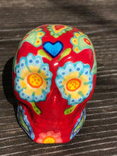 Load image into Gallery viewer, This hand-painted Mini Dia de Los Muertos ceramic skull art provides a vibrant representation of summertime blooms. Its fire red and nature-inspired design is unique, capturing the energy and beauty of a hot day at Meadowlark Gardens in Virginia. A perfect addition to any art collection. Measurements: H 2 3/4” x W 2” x D 2”