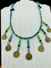 Load image into Gallery viewer, This necklace features vivid green and blue glass beading and a yin yang brass octagon charm. Each side of the charm is distinct, creating a two-in-one look. The look is further enhanced with the addition of rectangular rainbow hematite beads for added visual complexity. Double-hole flat matte gold beads keep the collar shape and add to the necklace's elegant draping when worn.  Measurements:    Necklace is 23” in length