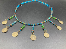 Load image into Gallery viewer, This necklace features vivid green and blue glass beading and a yin yang brass octagon charm. Each side of the charm is distinct, creating a two-in-one look. The look is further enhanced with the addition of rectangular rainbow hematite beads for added visual complexity. Double-hole flat matte gold beads keep the collar shape and add to the necklace's elegant draping when worn.  Measurements:    Necklace is 23” in length